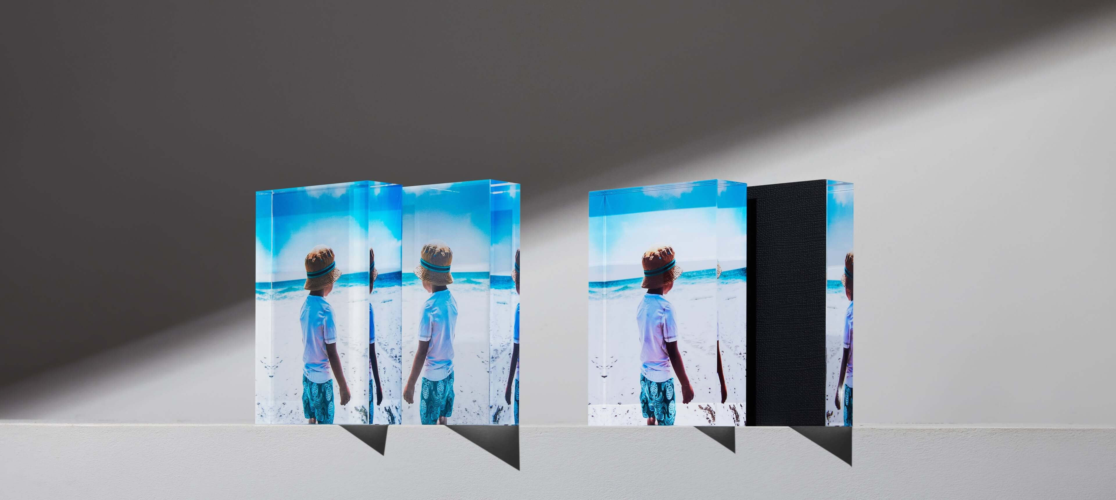 two sets of acrylic photo blocks standing on a white table showing a kid on the beach