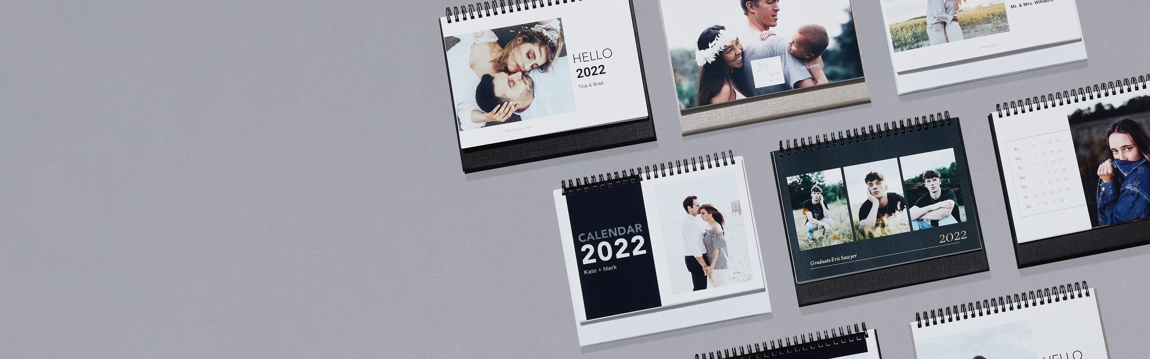 eight desk calendars on a grey table showing different designs