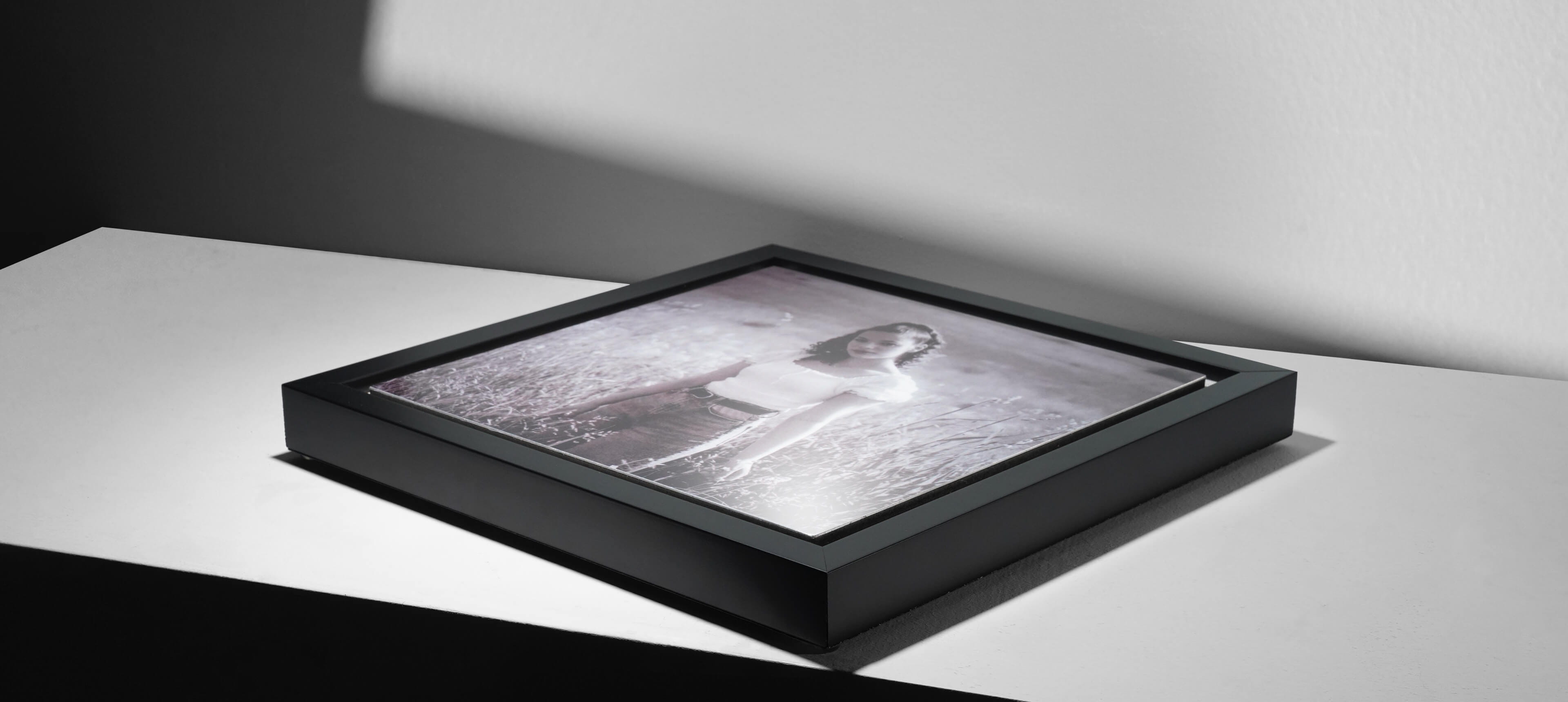 framed metal print on grey table showing woman in field