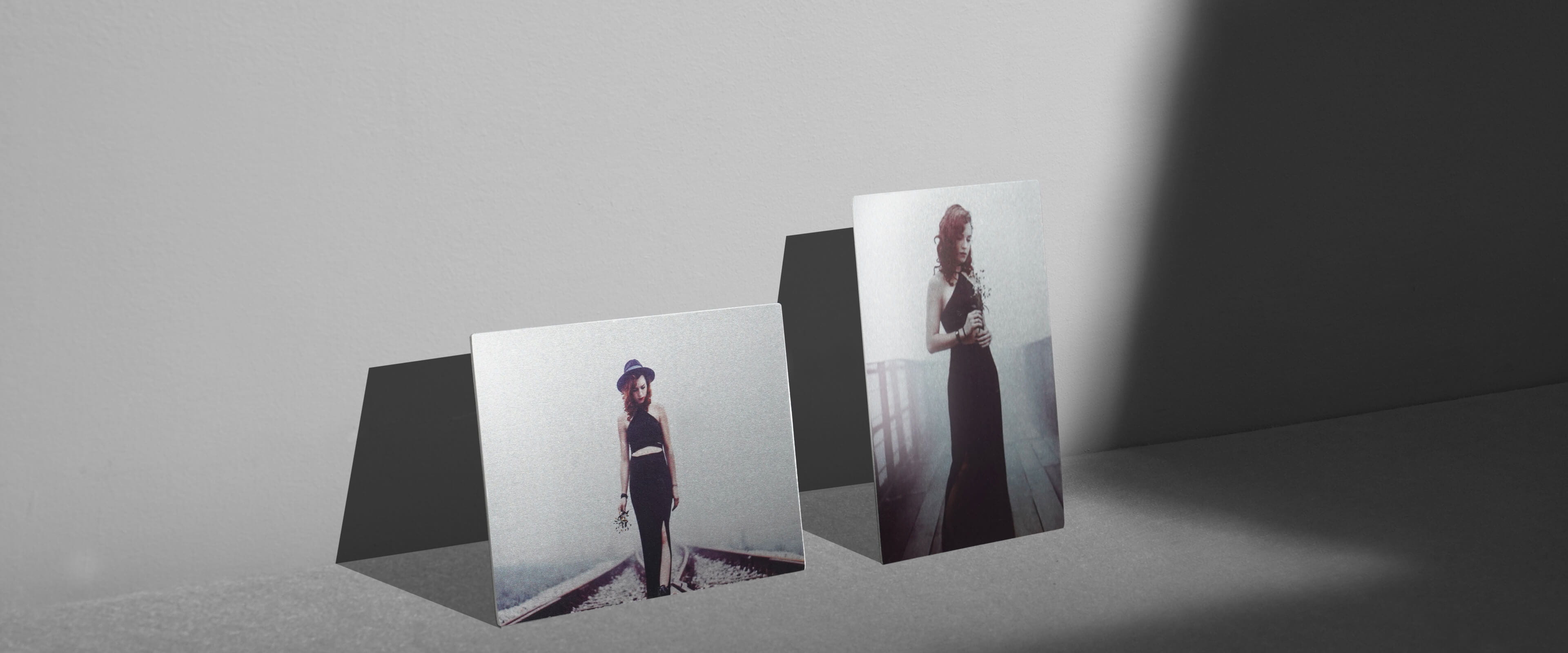 a tabletop metal print on grey table showing a woman in black dress