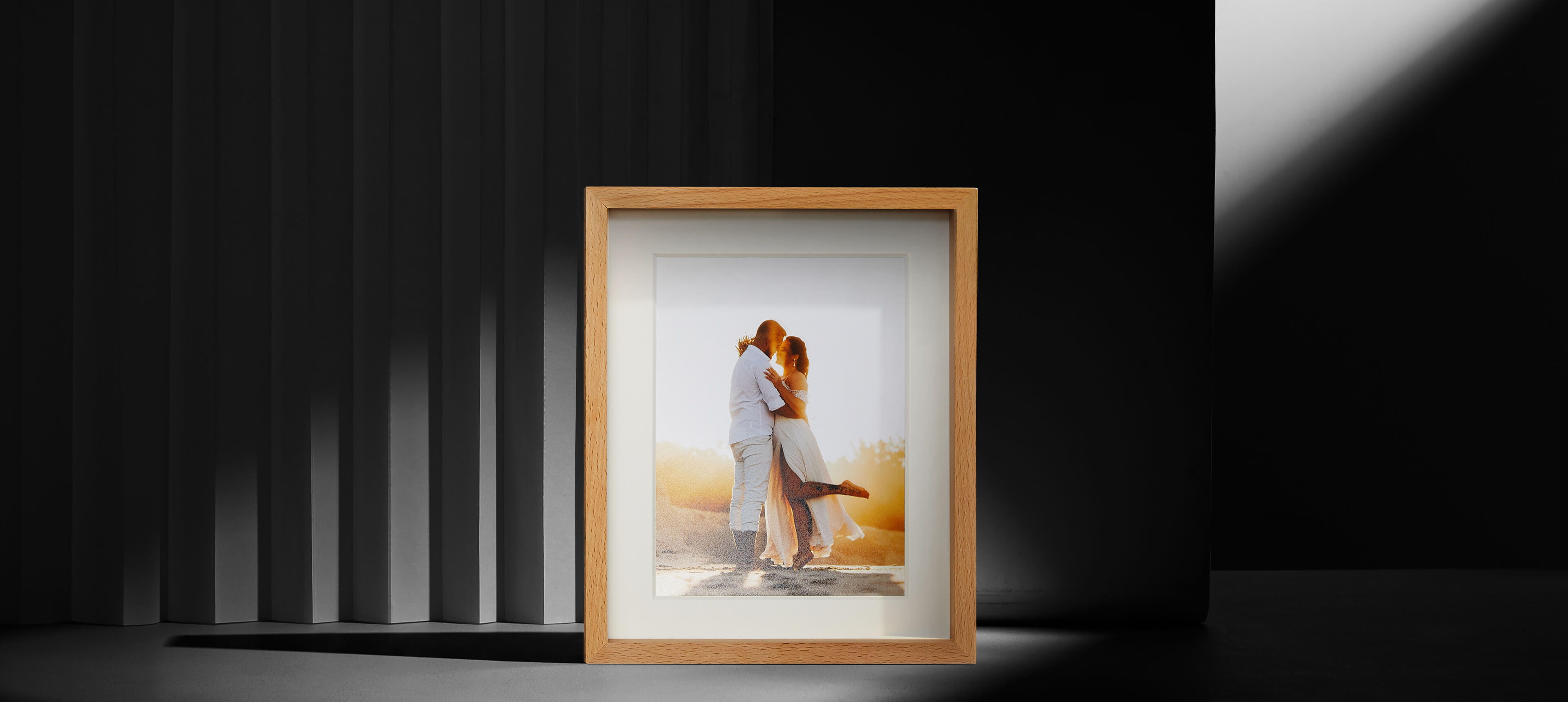a slide-in print stand on a grey table showing a couple embracing on a beach