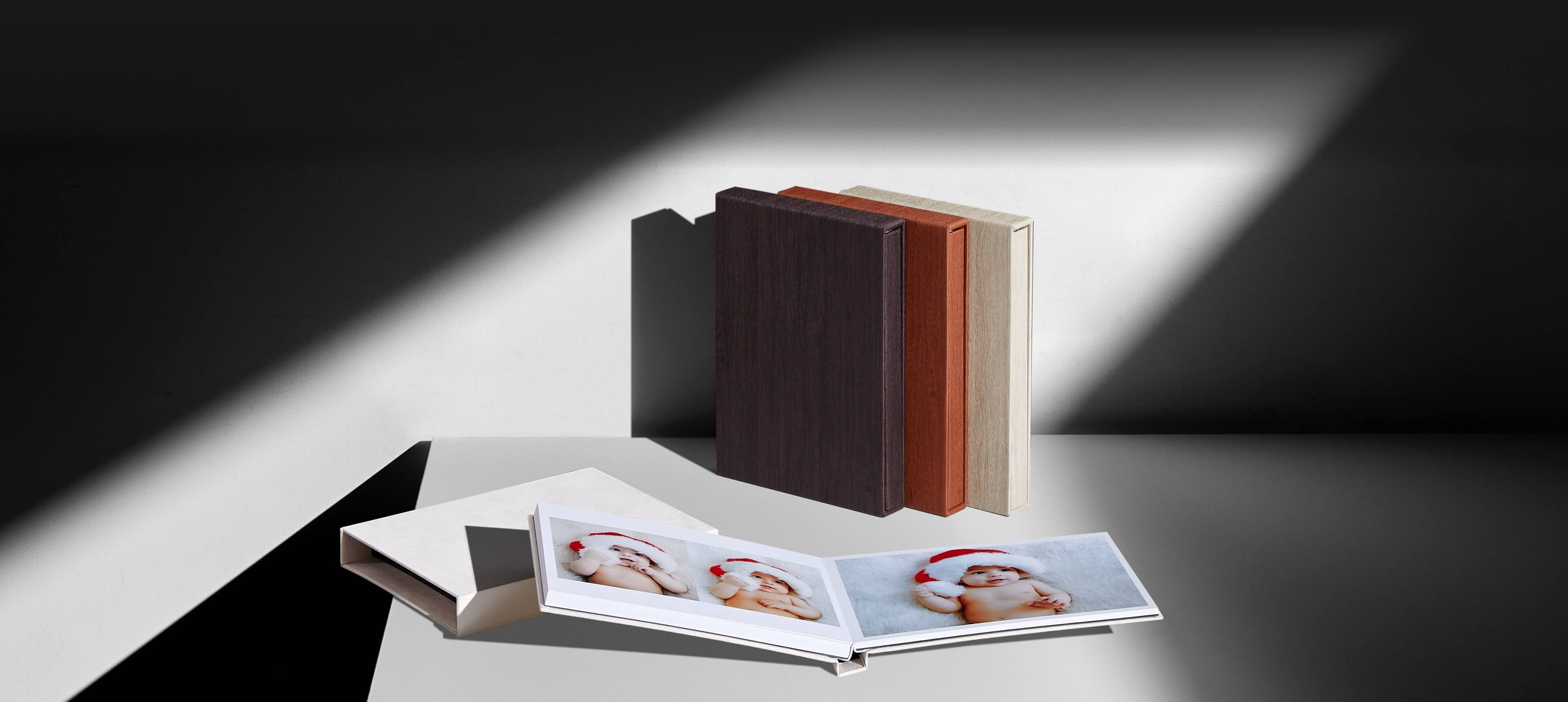 a slipcase album set showing a photo album opened resting on a cream suede box